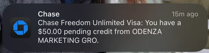 Credit card notification showing a $50.00 pending credit from Odenza Marketing Group
