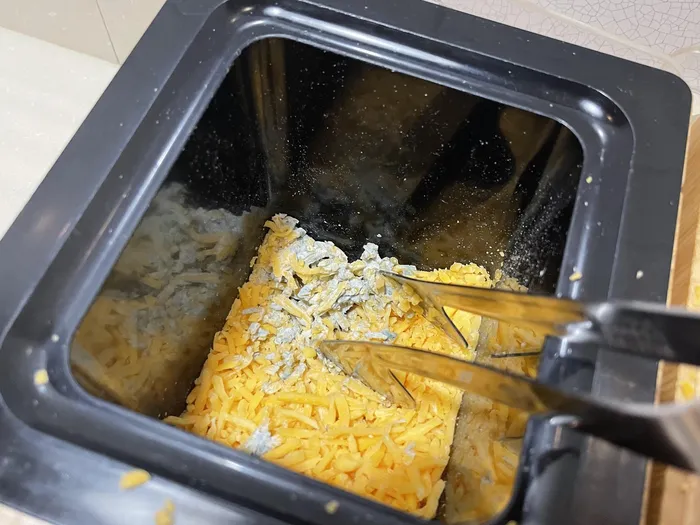 Close-up of the moldy cheese found at the bottom of the shredded cheese bin